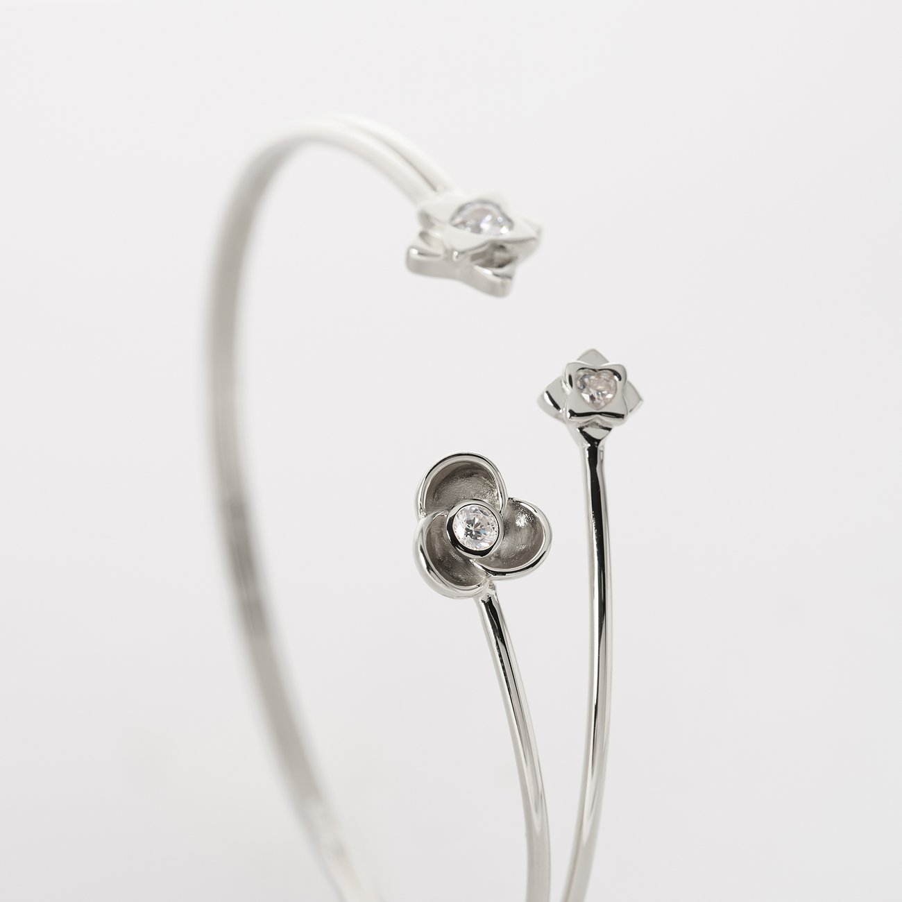 Nahaufnahme eines JETTE Armreifs aus recyceltem 925er Silber mit Zirkonia-Blütenmotiven, leicht von oben gesehen.
