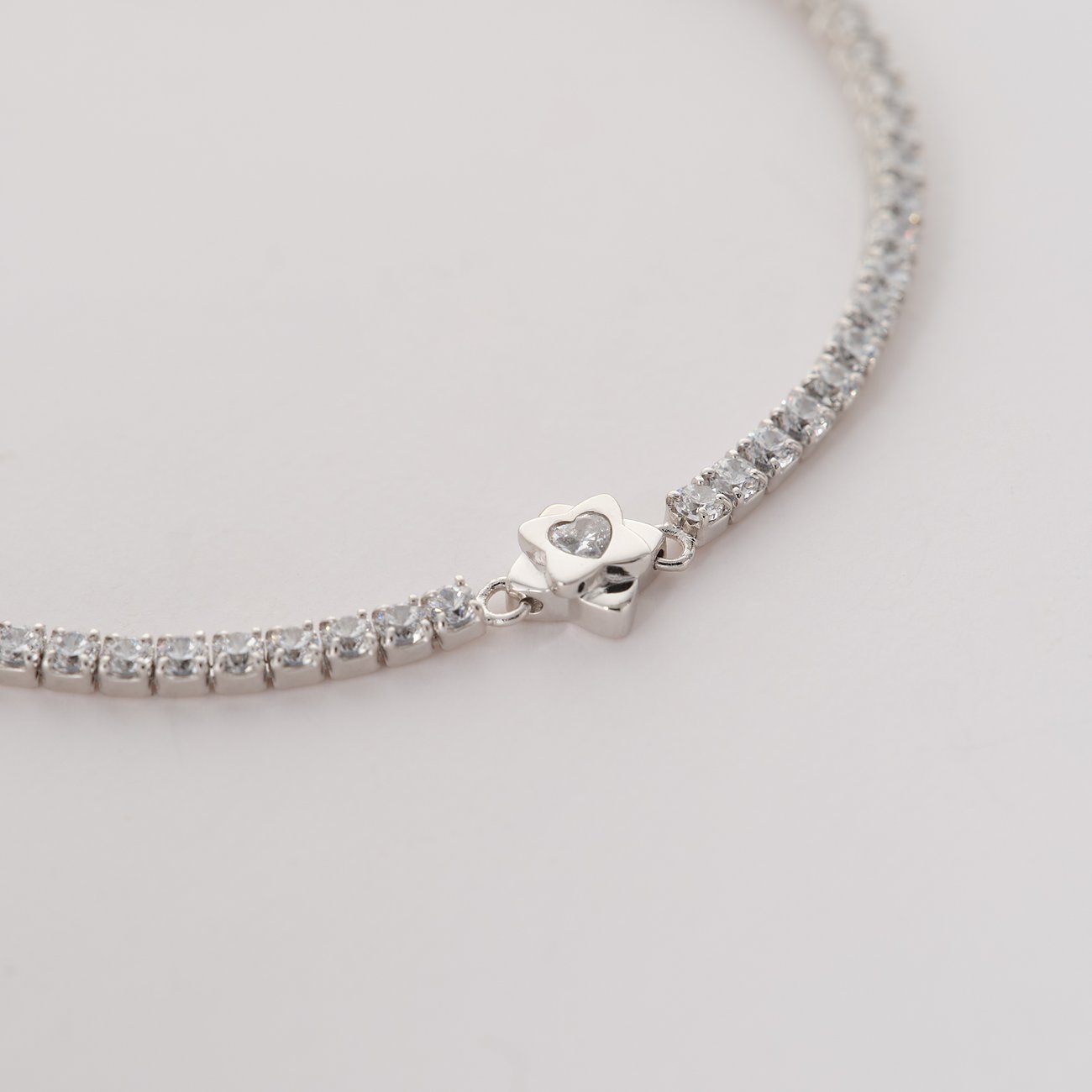 Nahaufnahme eines JETTE Armbands aus recyceltem 925er Silber mit funkelnden Zirkonia-Farbsteinen und einem Herzverschluss.