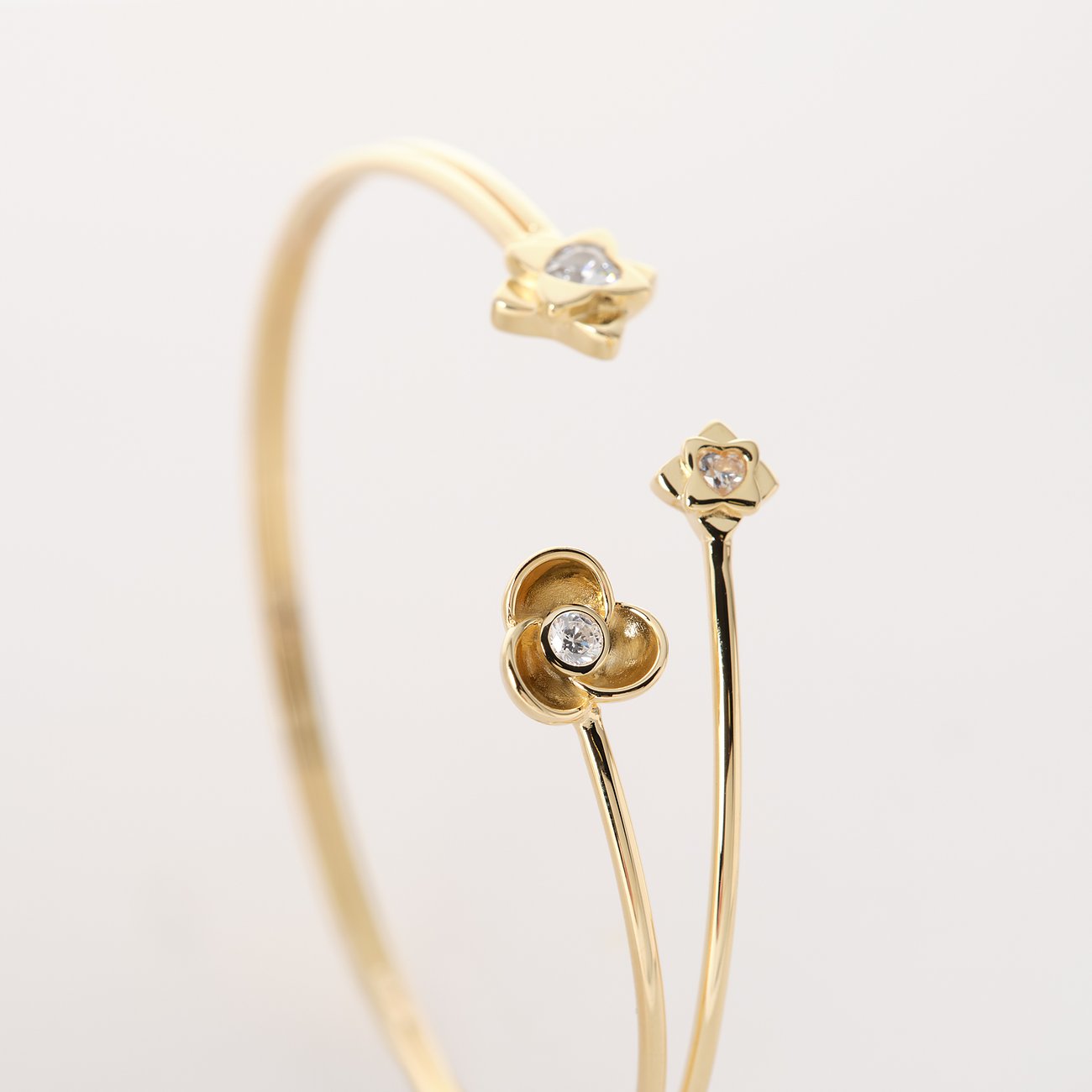 JETTE Armschmuck aus recyceltem, goldfarbenem 925er Silber mit Zirkonia-besetzten Blütenmotiven, im Detail.