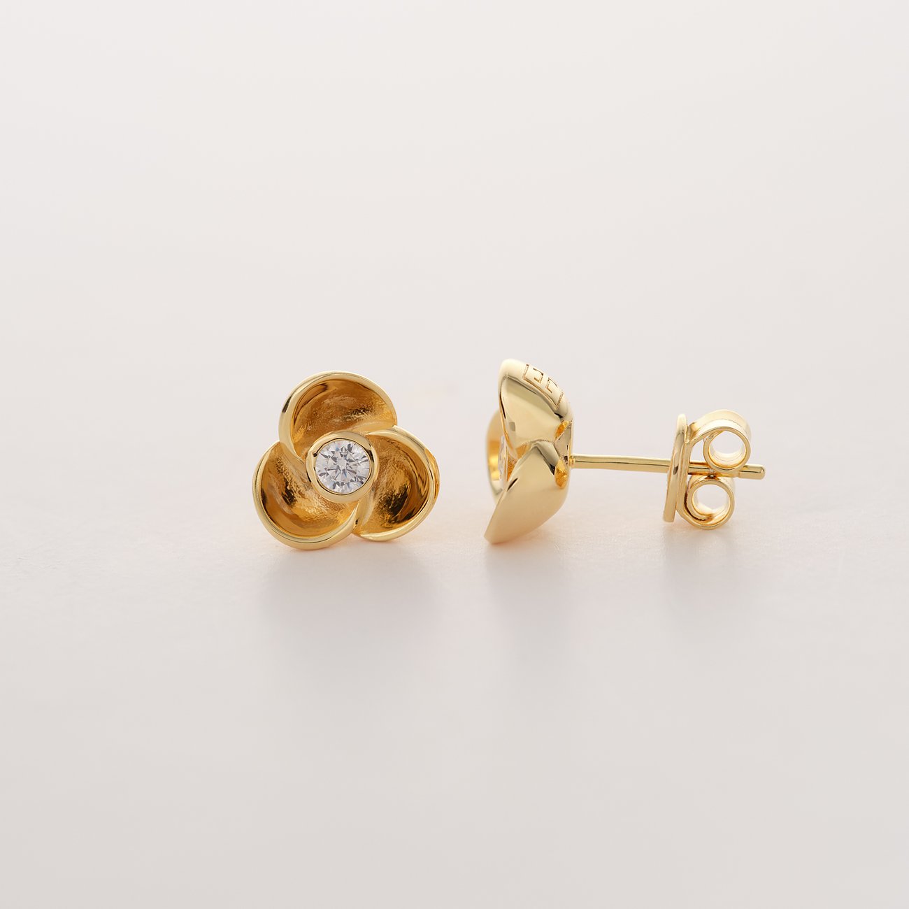 JETTE Ohrstecker aus recyceltem, vergoldetem 925er Silber in Blütenform mit einem Zirkonia in der Mitte.