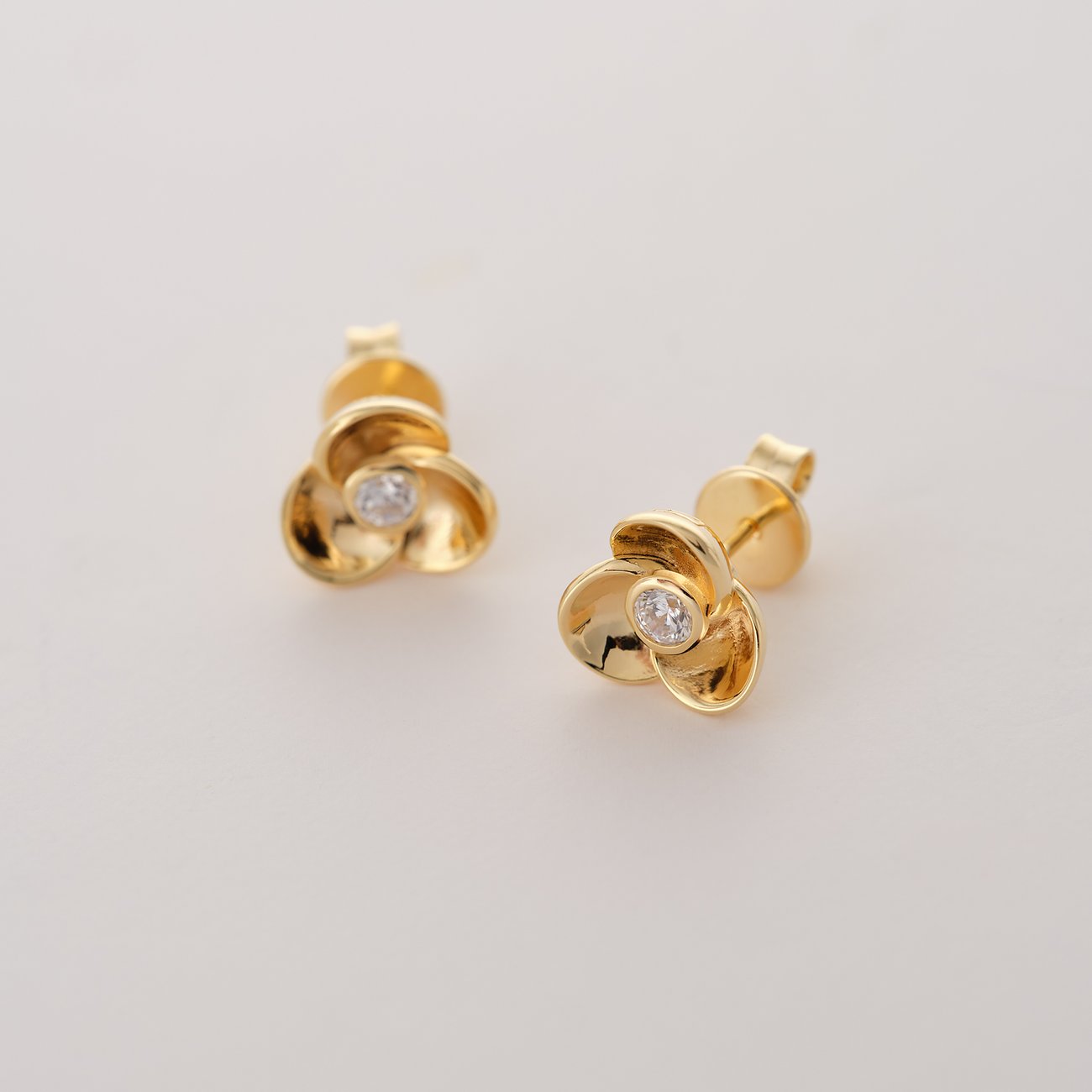JETTE Ohrstecker aus recyceltem 925er Silber in Gold, geformt wie Blüten mit einem Zirkonia-Stein.
