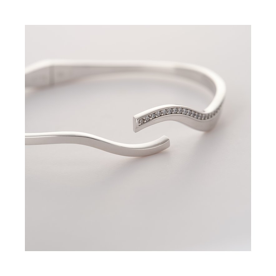 Nahaufnahme eines JETTE Armreifs aus recyceltem 925er Silber mit Zirkonia-Steinen in einer wellenförmigen Reihe.