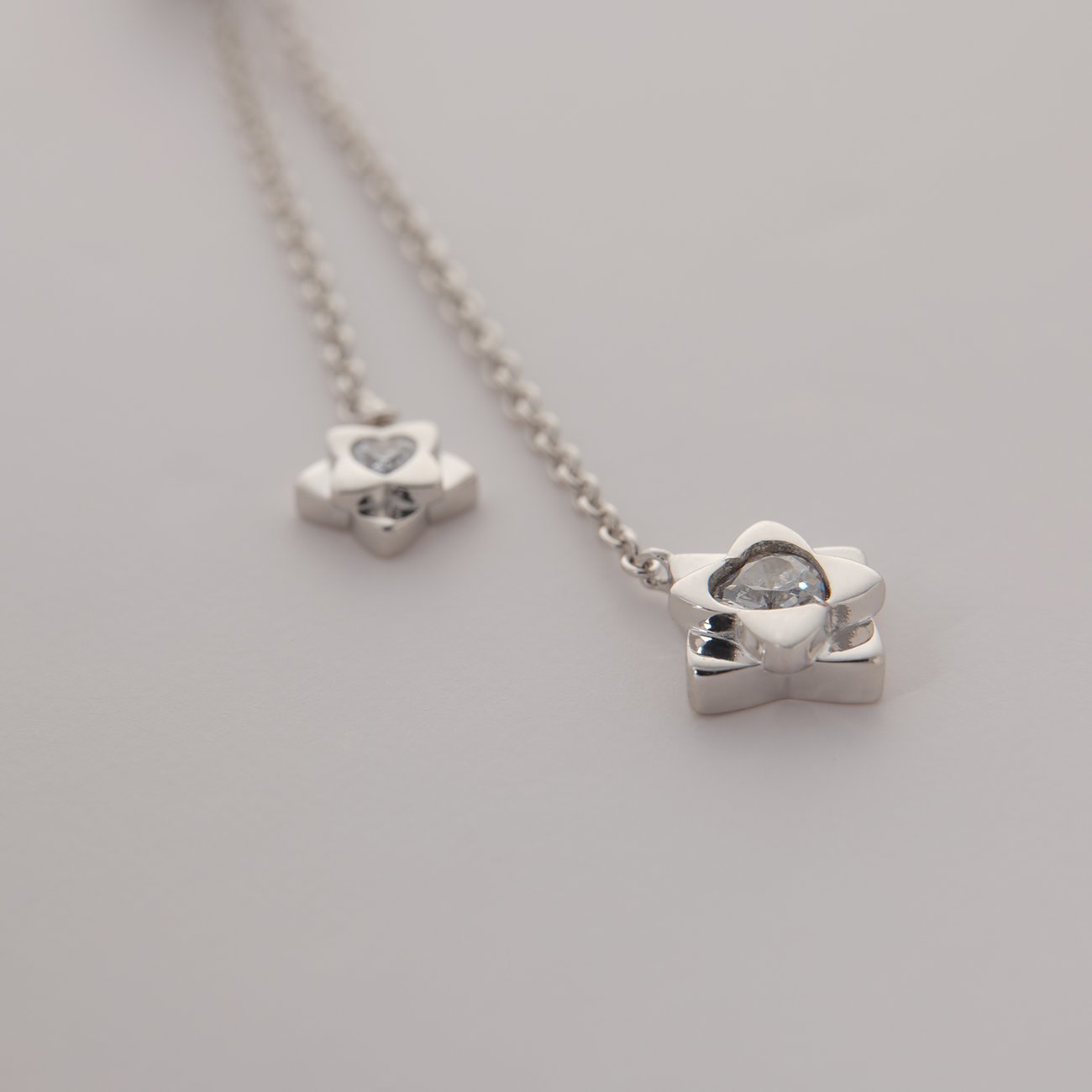 Primo piano di una collana JETTE in argento 925 riciclato con due ciondoli a fiore in zirconia.