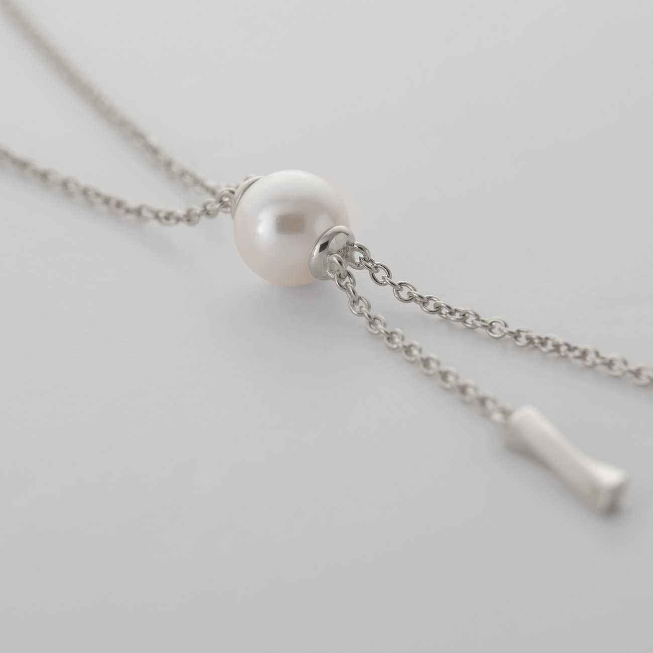 Nahaufnahme einer JETTE Silberkette aus recyceltem 925er Silber mit einer einzelnen weißen Perle in der Mitte.