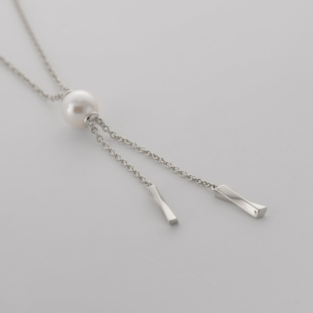 JETTE Halsschmuck aus recyceltem Silber 925 mit einer Perle und zwei spiralförmigen Endstücken.