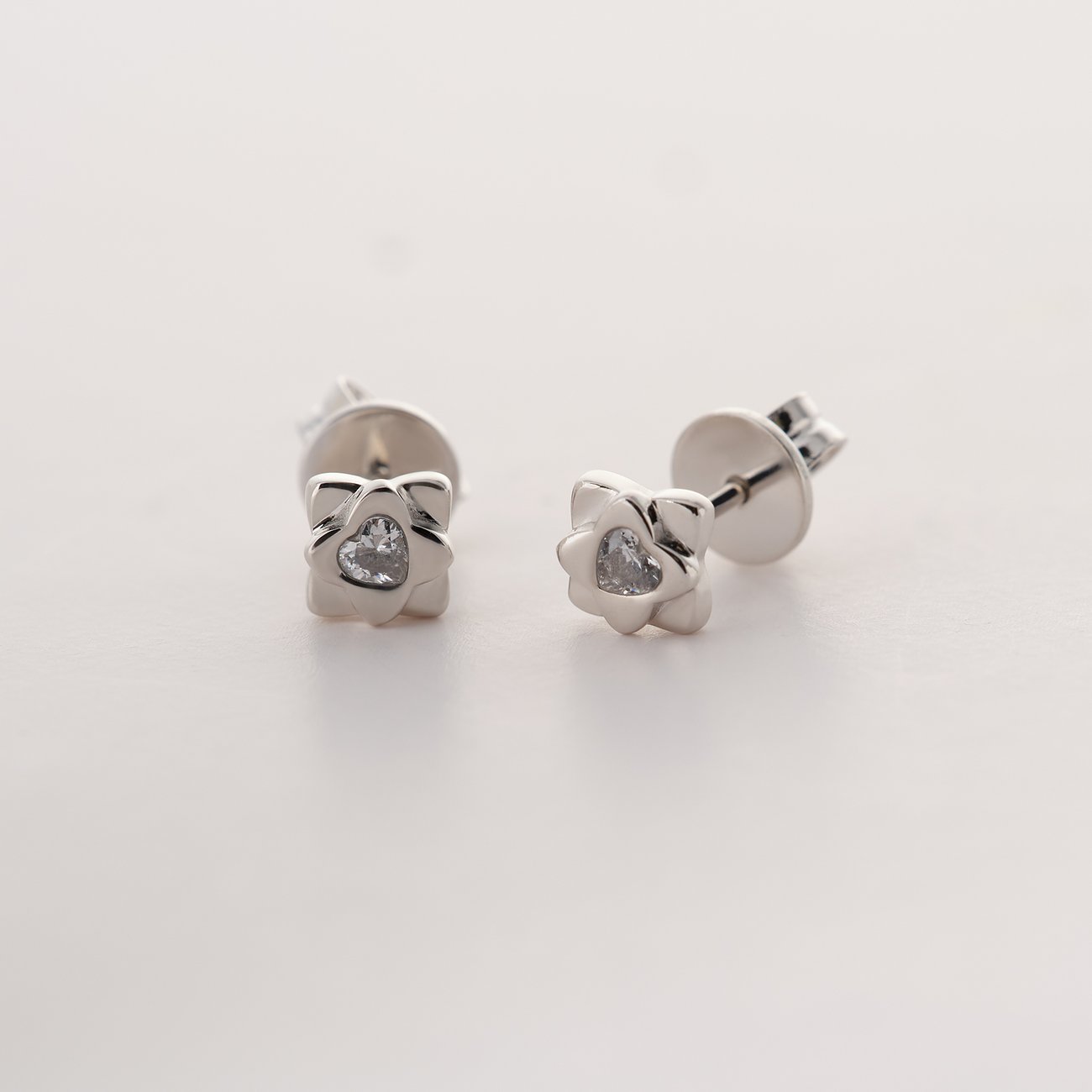 Zwei JETTE Ohrstecker aus recyceltem 925er Silber, jeweils mit einem hellen Zirkonia in Herzform in der Mitte.