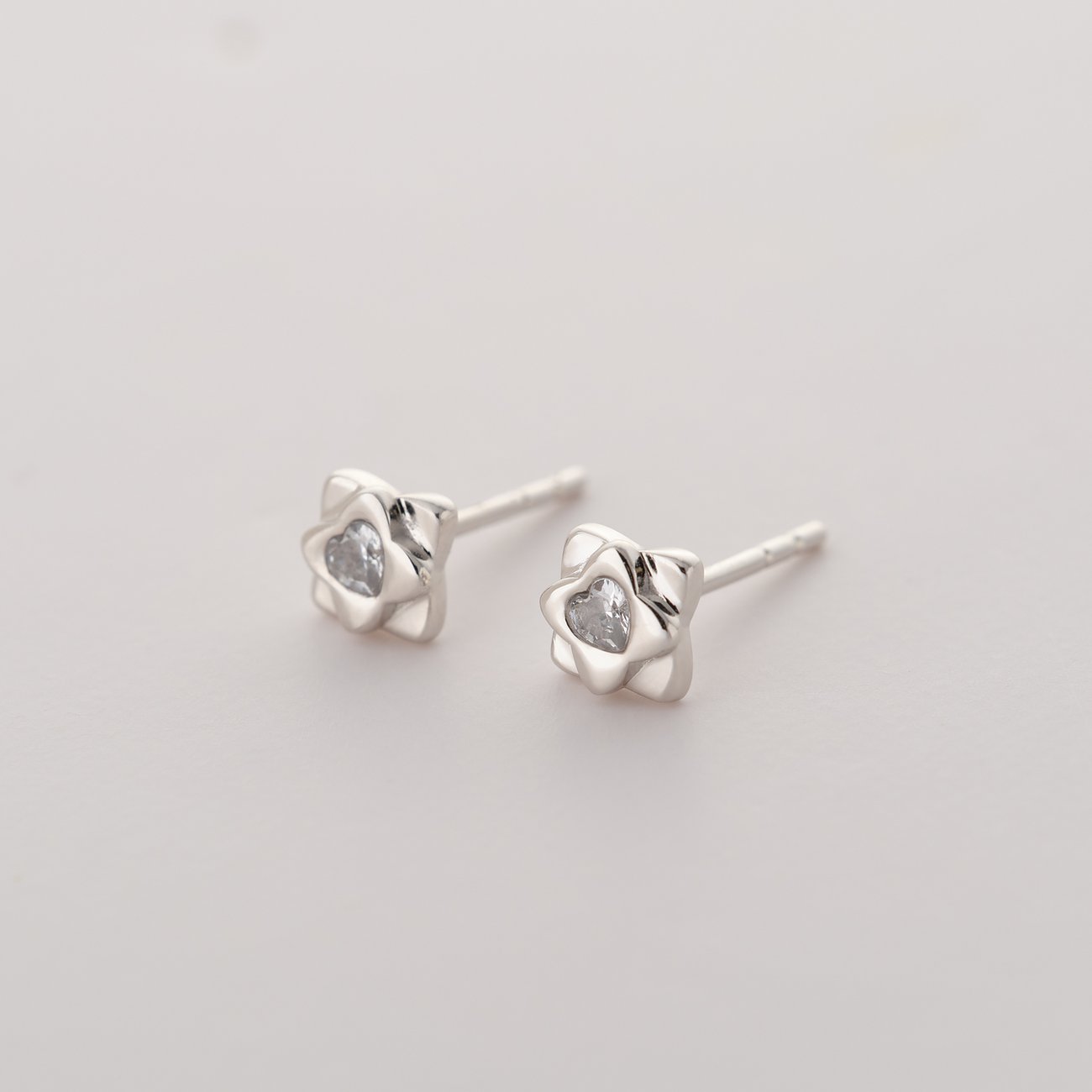 Ein Paar JETTE Ohrstecker aus recyceltem 925er Silber in Blütenform, besetzt mit einem glitzernden Zirkonia.