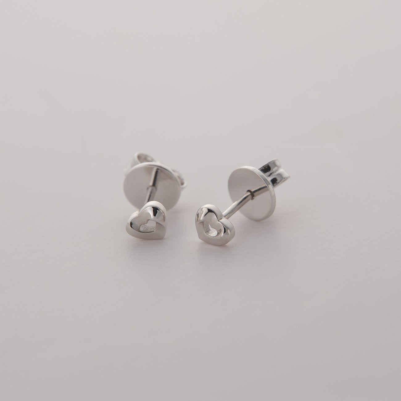 JETTE Ohrstecker aus recyceltem Silber in Herzform, seitliche Ansicht, auf einem weißen Hintergrund.