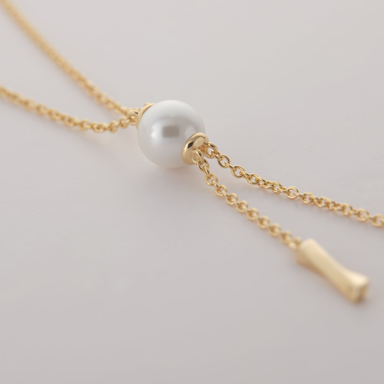 Nahaufnahme einer JETTE Halskette aus recyceltem 925er Silber. Eine weiße Perle ist mittig auf einer goldfarbenen Kette.