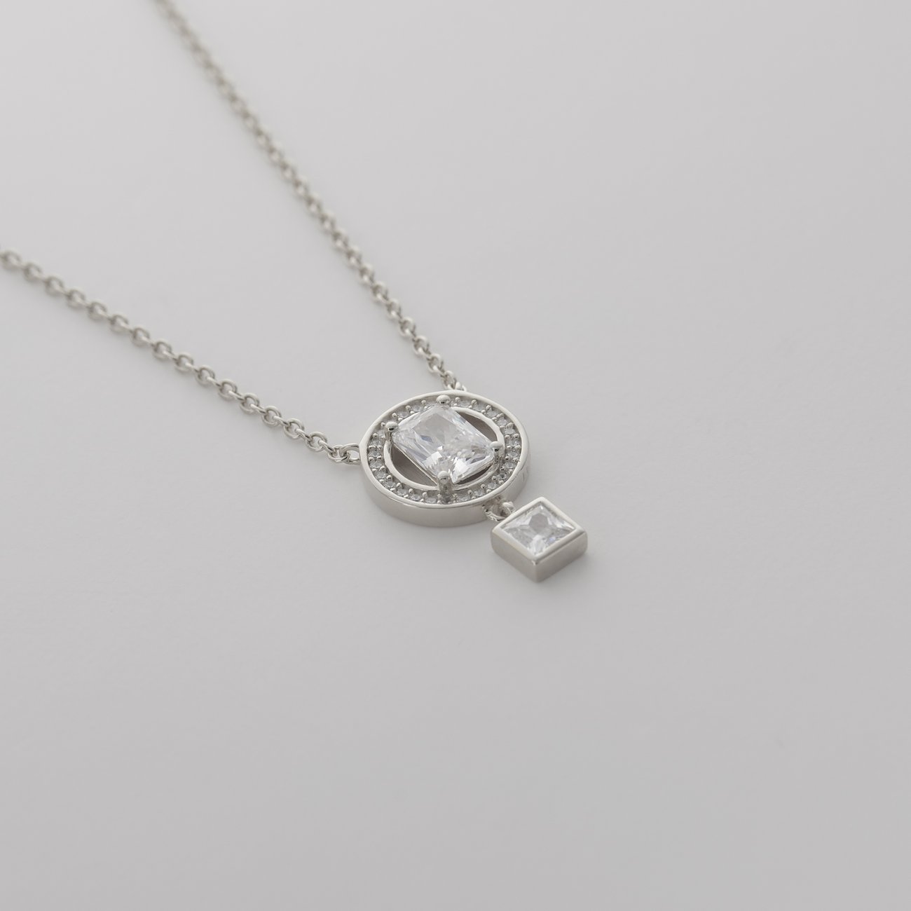 JETTE Halskette: recyceltes 925er Silber. Kreisförmiger Anhänger mit rechteckigem Zirkonia, umgeben von kleinen Zirkonia.
