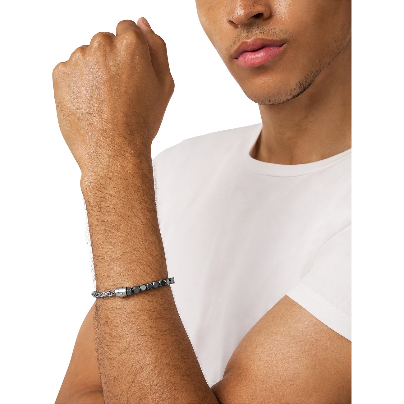 Diesel Armschmuck aus Edelstahl mit Hämatit-Farbsteinen am Handgelenk eines Mannes, der ein weißes T-Shirt trägt.