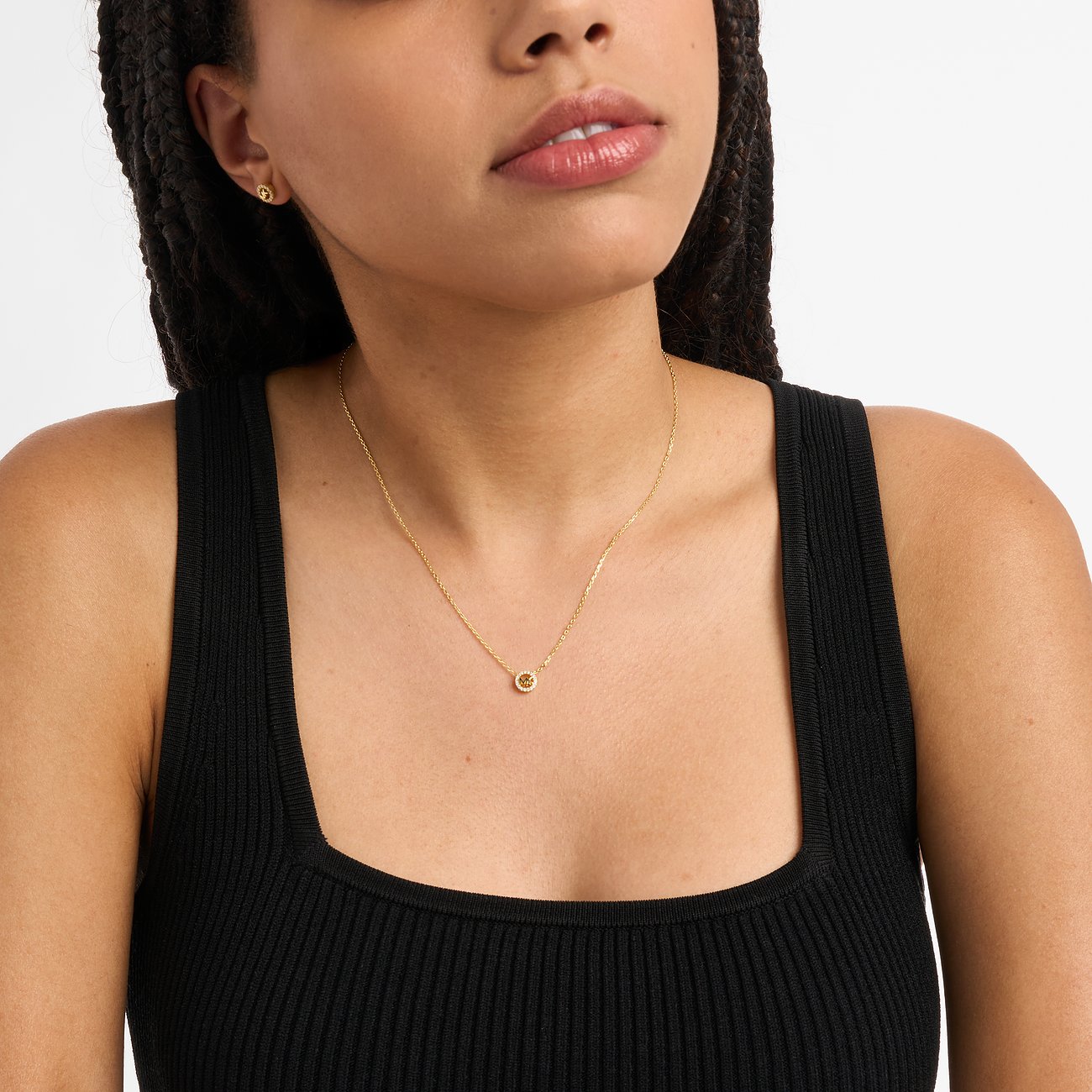 Eine Frau trägt ein Michael Kors Schmuckset aus goldfarbenem Silber mit Zirkonia, bestehend aus einer Kette und Ohrsteckern.