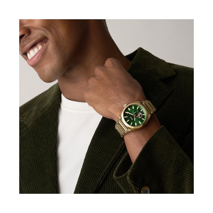 Uomo con giacca in velluto a coste verde indossa orologio Fossil color oro, quadrante verde al polso.