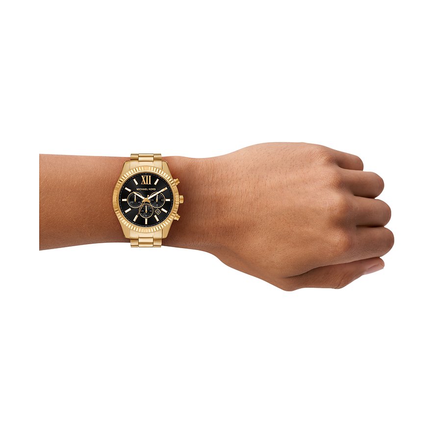 Goldfarbene Michael Kors Armbanduhr aus Edelstahl am Handgelenk. Schwarzes Zifferblatt mit römischen Ziffern.