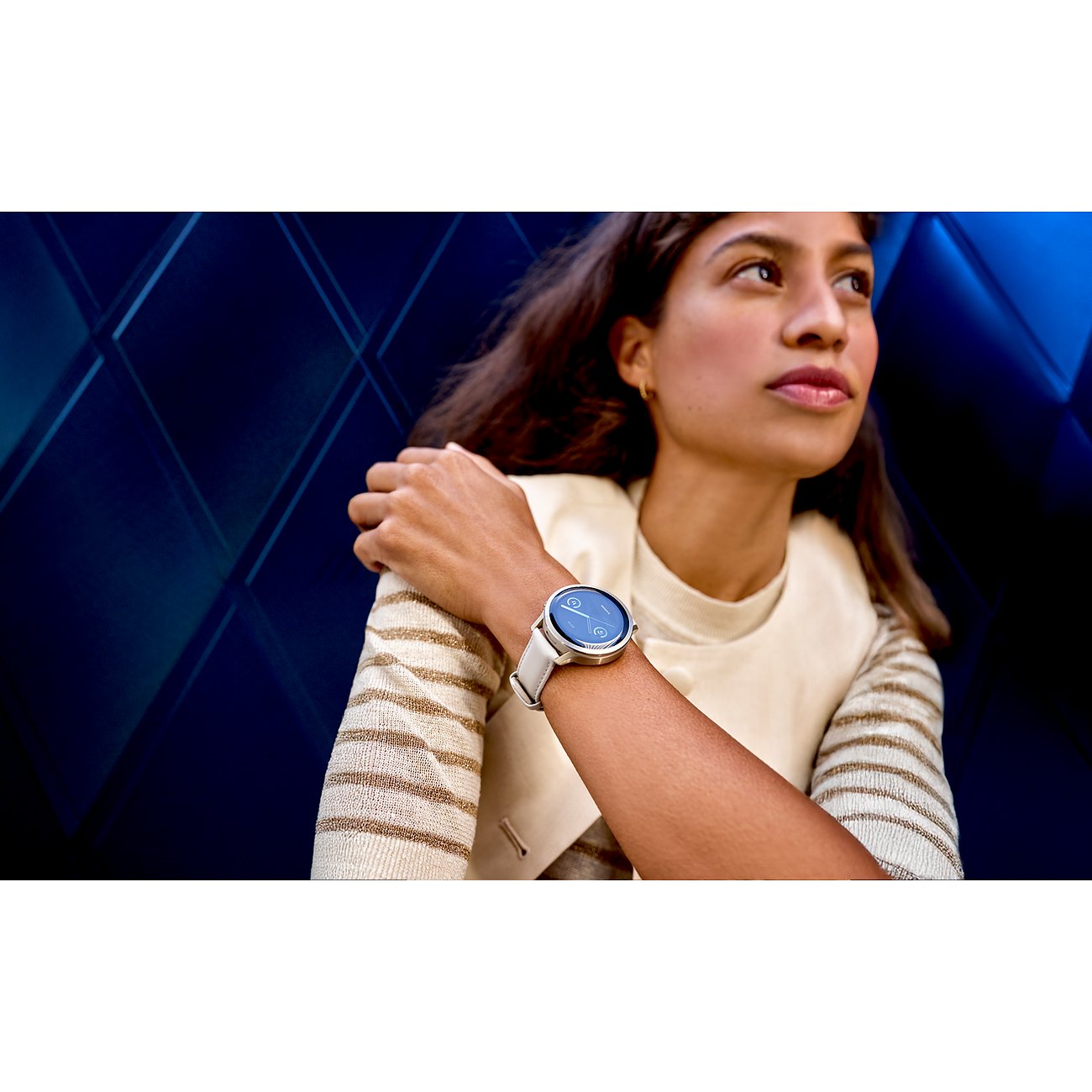 Eine Frau trägt eine Garmin Smartwatch aus Kunststoff mit weißem Armband am linken Handgelenk.