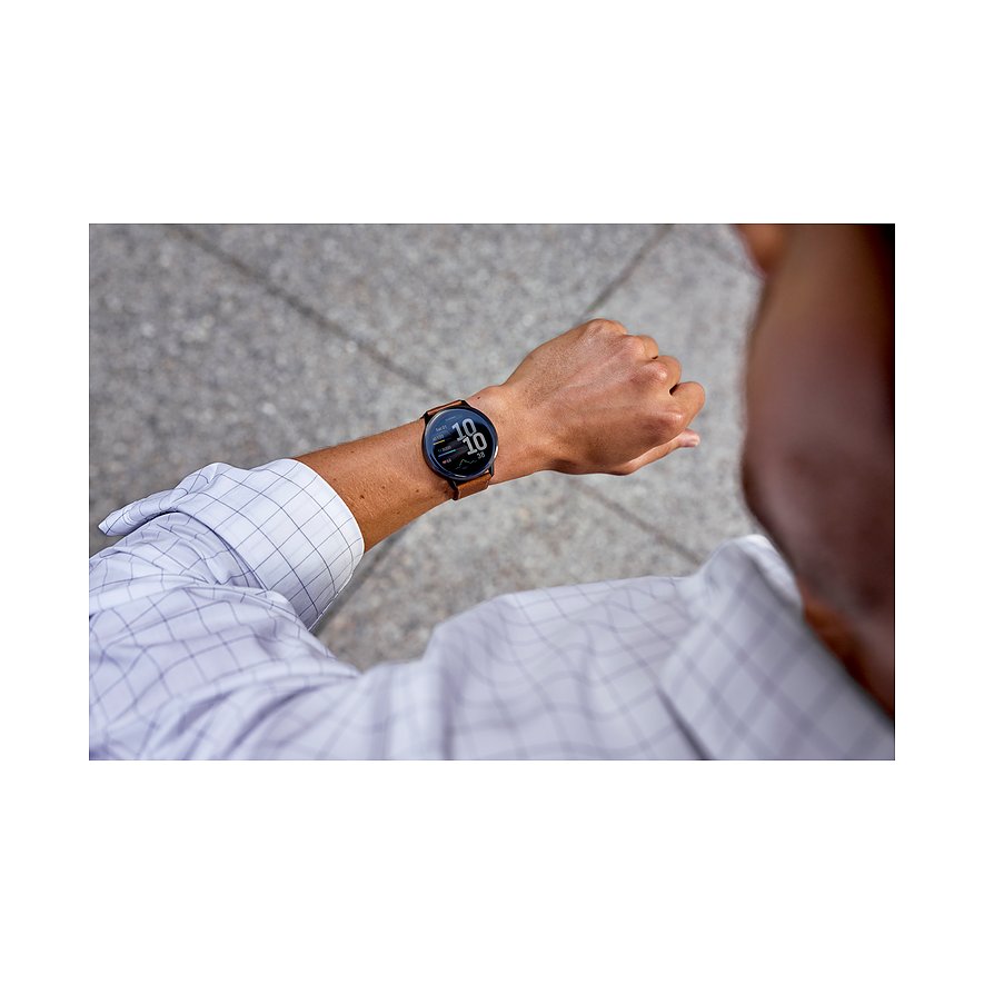 Nahaufnahme einer Garmin Smartwatch mit braunem Kunststoffarmband am linken Handgelenk eines Mannes, der auf die Uhrzeit schaut.