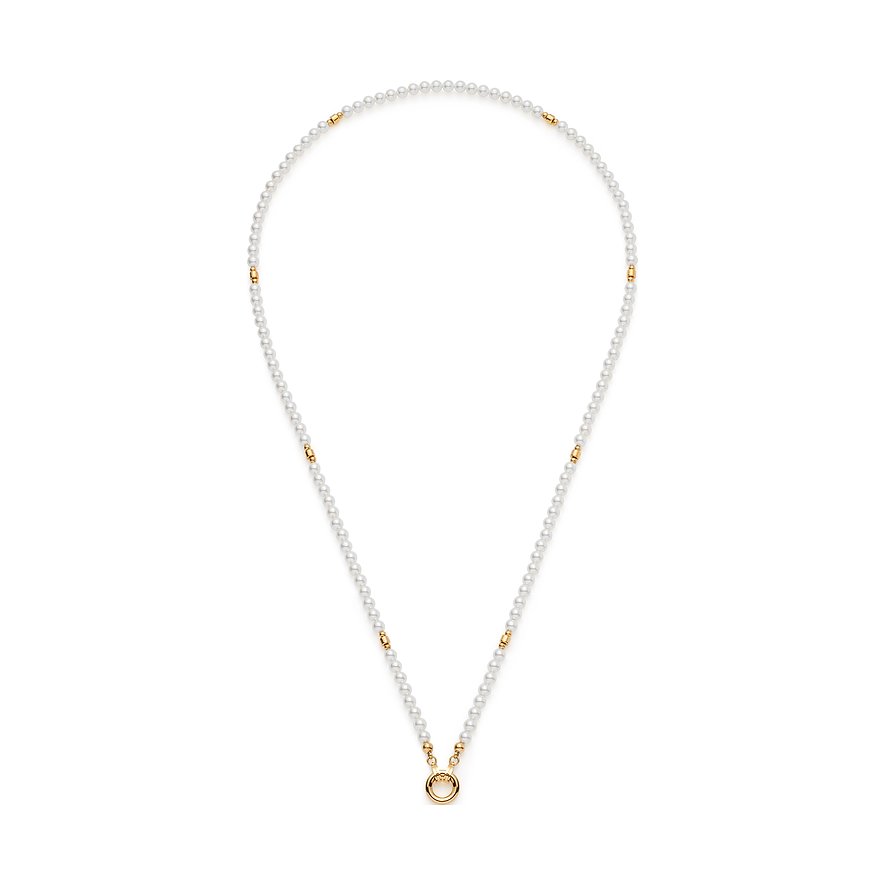 Leonardo RVS parelketting met kleine witte parels en gouden accenten, van boven hangend, toont ring.