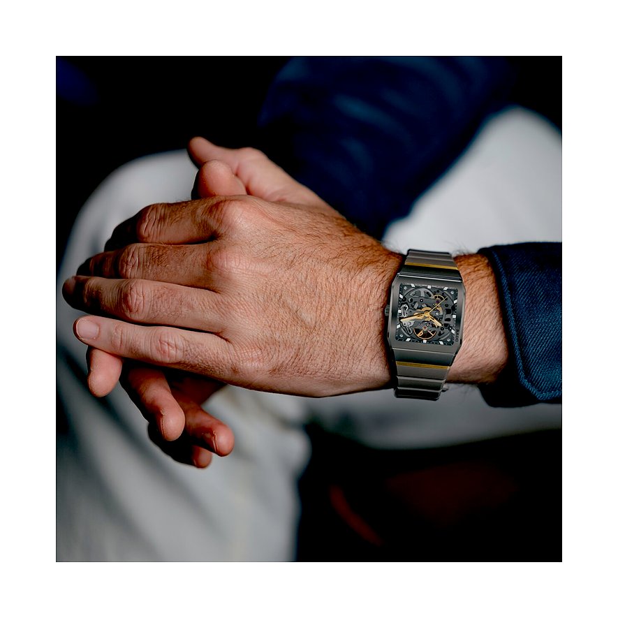 Nahaufnahme einer Rado Herrenuhr aus Keramik am Handgelenk eines Mannes, mit rechteckigem Gehäuse und Golddetails.