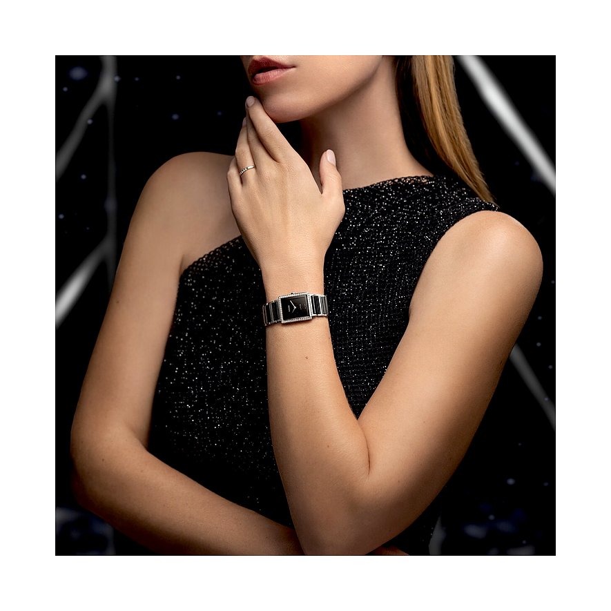 Eine Frau trägt eine Rado Damenuhr aus Edelstahl mit Diamanten und schwarzem Zifferblatt an ihrem linken Handgelenk.