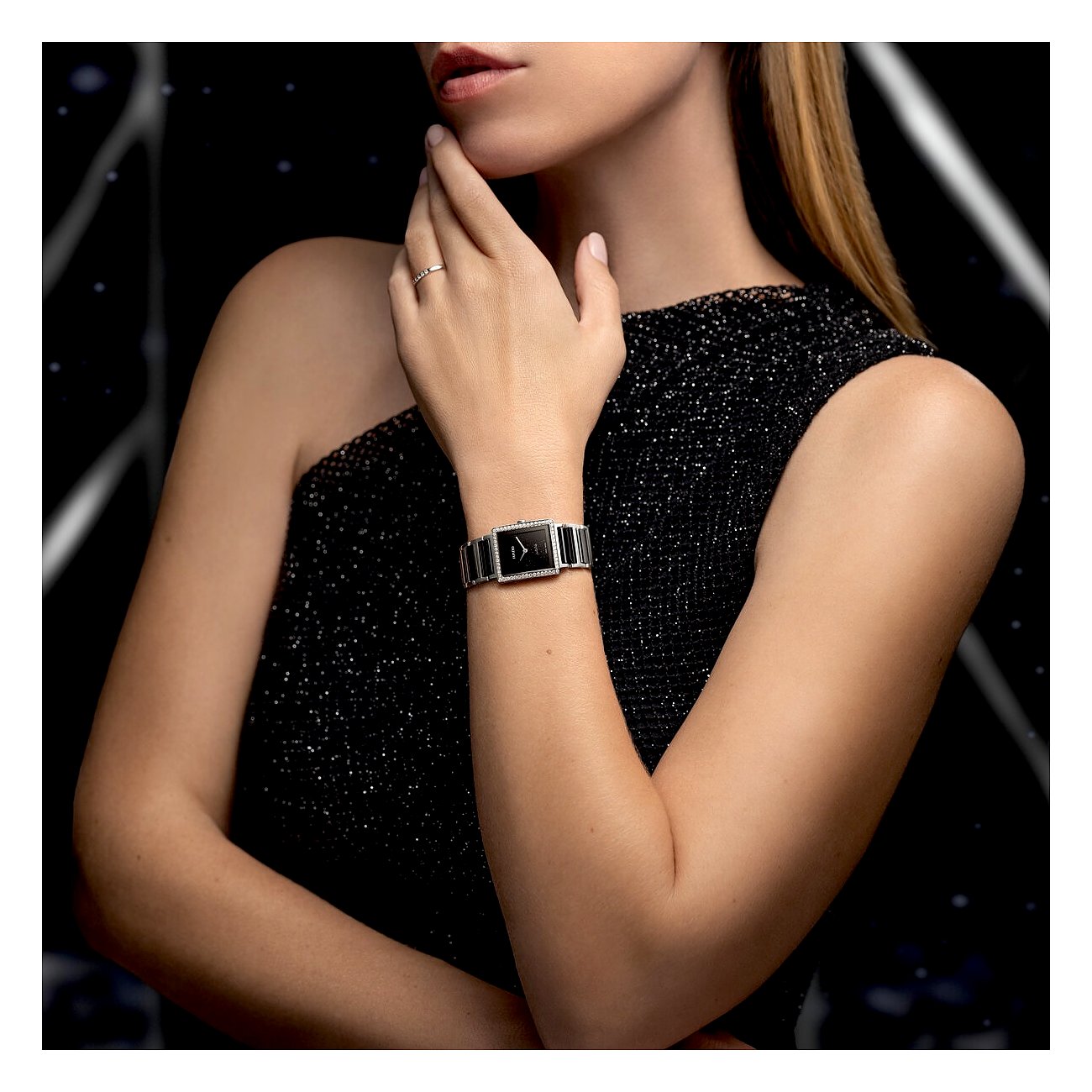Eine Frau trägt eine Rado Damenuhr aus Edelstahl mit Diamanten und schwarzem Zifferblatt an ihrem linken Handgelenk.