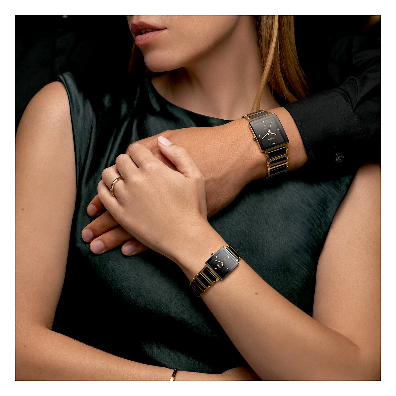 Nahaufnahme von zwei Händen, die Rado Damenuhren aus Edelstahl mit Diamanten und schwarzem Zifferblatt tragen.