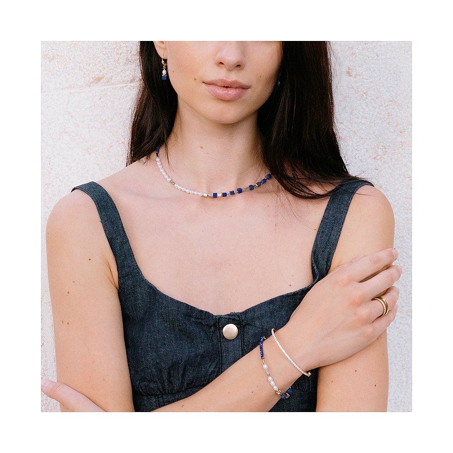 Una donna indossa una collana Coeur de Lion in acciaio inossidabile con perle blu, trasparenti e dettagli dorati.