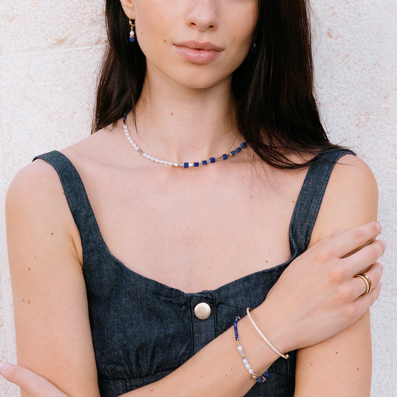 Una donna indossa una collana Coeur de Lion in acciaio inossidabile con perle blu, trasparenti e dettagli dorati.