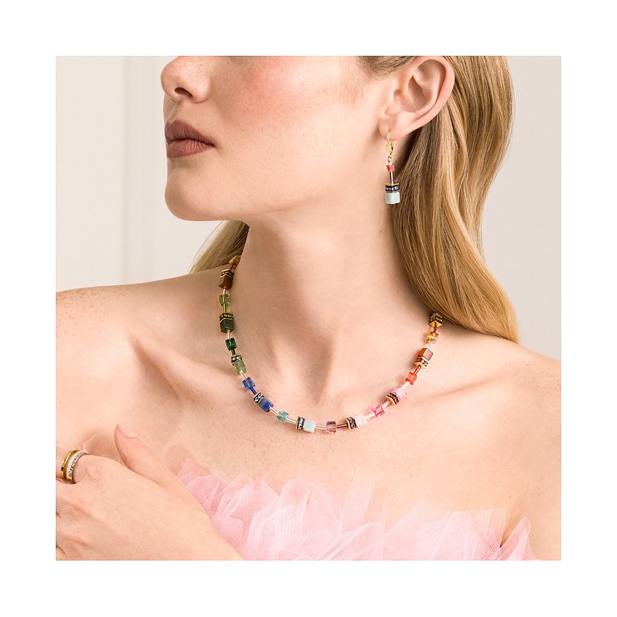 Una donna indossa una collana Coeur de Lion in acciaio inossidabile con pietre color avventurina e orecchini a cubo abbinati.