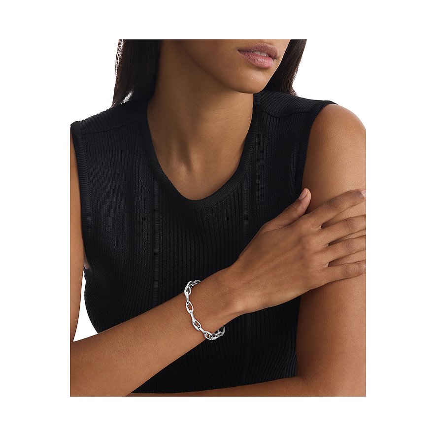 Model trägt ein Calvin Klein Armband aus Edelstahl mit ineinandergreifenden Gliedern an ihrem linken Handgelenk.