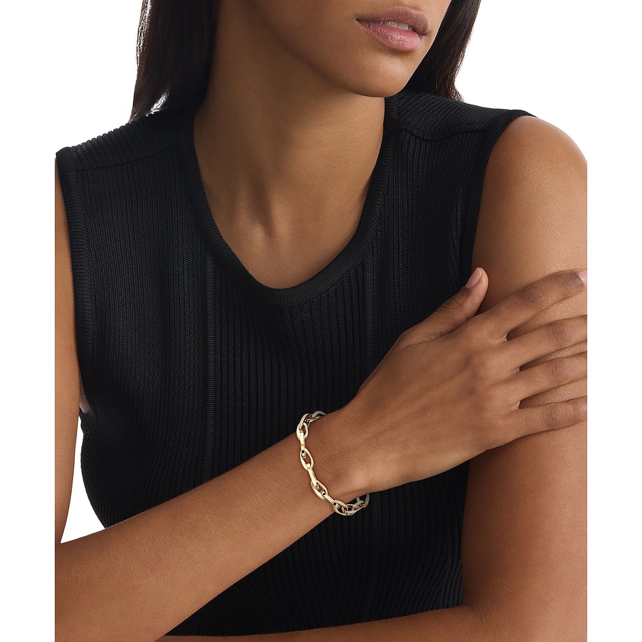 Ein Calvin Klein Armband aus goldfarbenem Edelstahl mit verbundenen, ovalen Gliedern am Handgelenk eines Models.