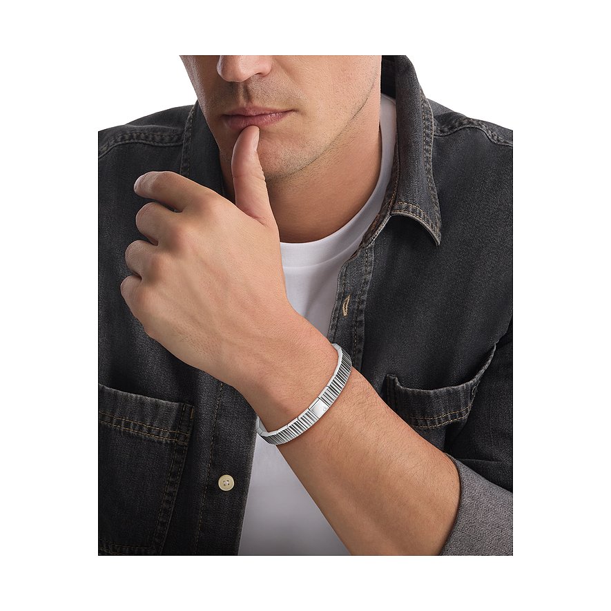 Ein Mann tr die Calvin Klein Armschmuck aus Edelstahl, der gerillt ist und ein glattes Mittelst aufweist.