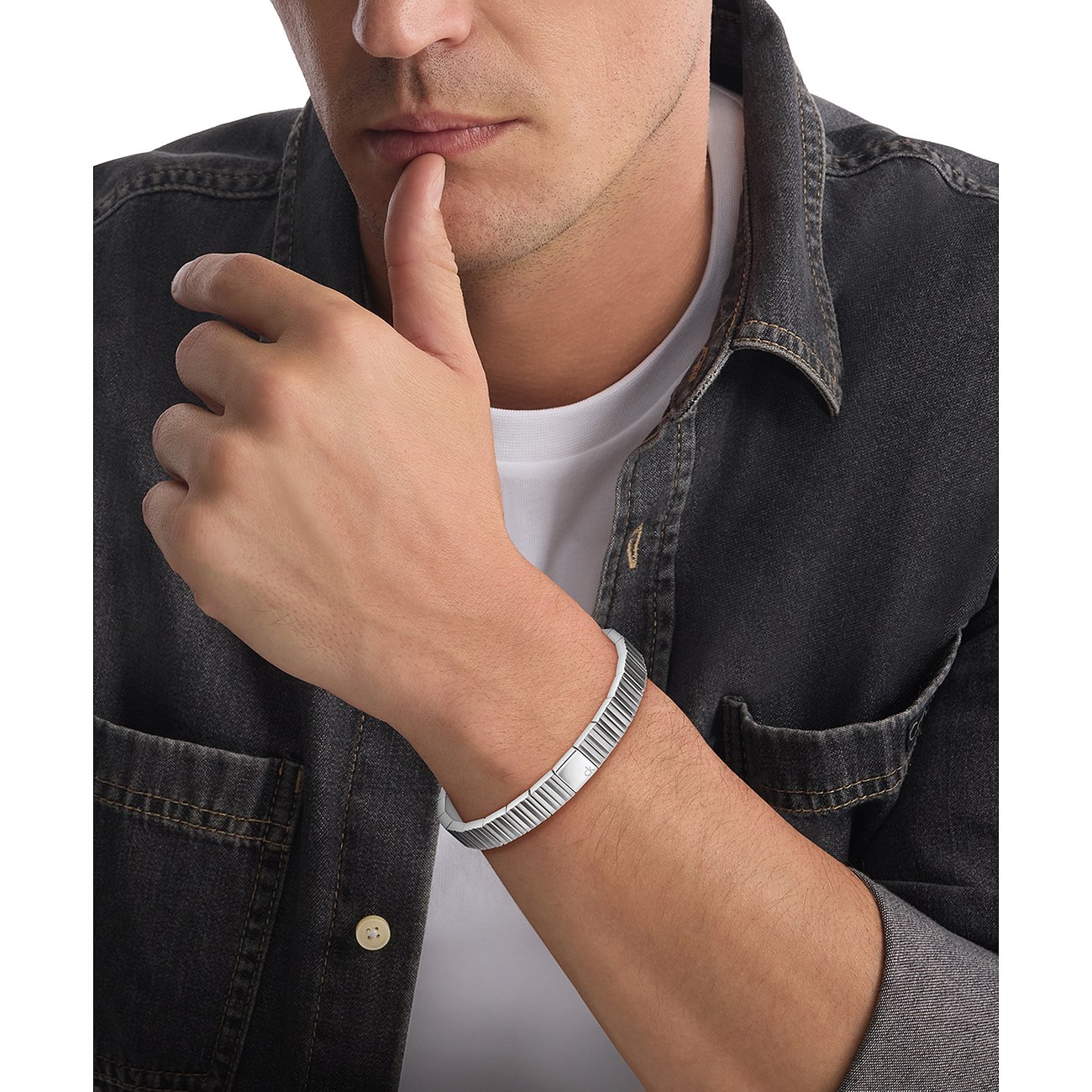 Ein Mann tr die Calvin Klein Armschmuck aus Edelstahl, der gerillt ist und ein glattes Mittelst aufweist.