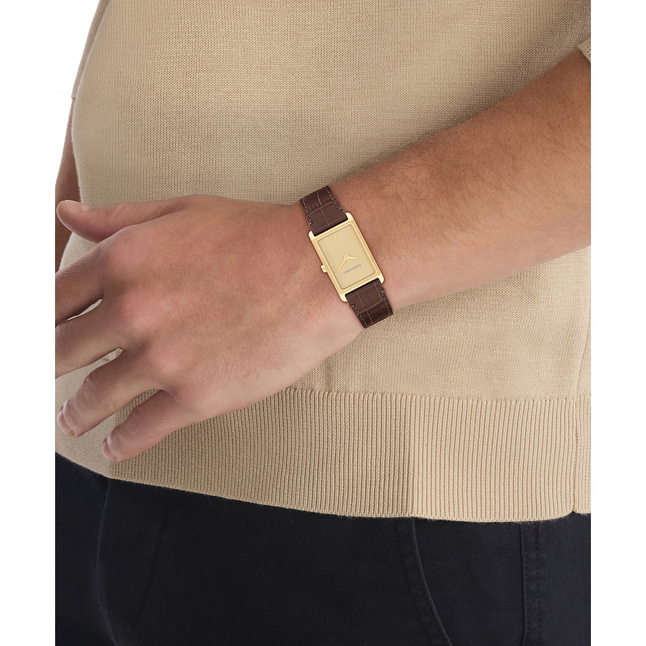 Calvin Klein herenhorloge van goudkleurig roestvrij staal met een eenvoudig wijzerblad en bruine leren band om de pols.