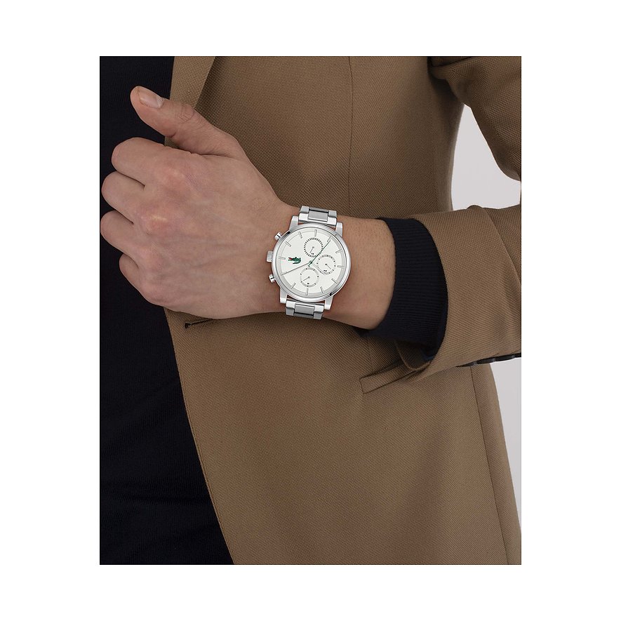 Am Handgelenk eines Mannes getragene Lacoste Herrenuhr aus Edelstahl mit weißem Zifferblatt und Chromdetails.
