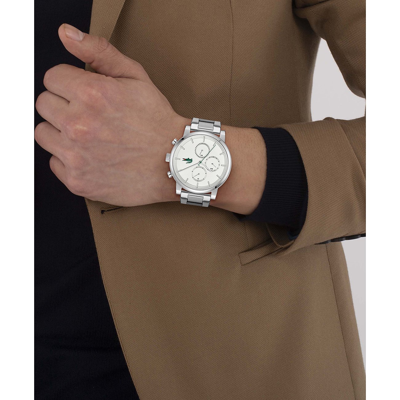 Am Handgelenk eines Mannes getragene Lacoste Herrenuhr aus Edelstahl mit weißem Zifferblatt und Chromdetails.