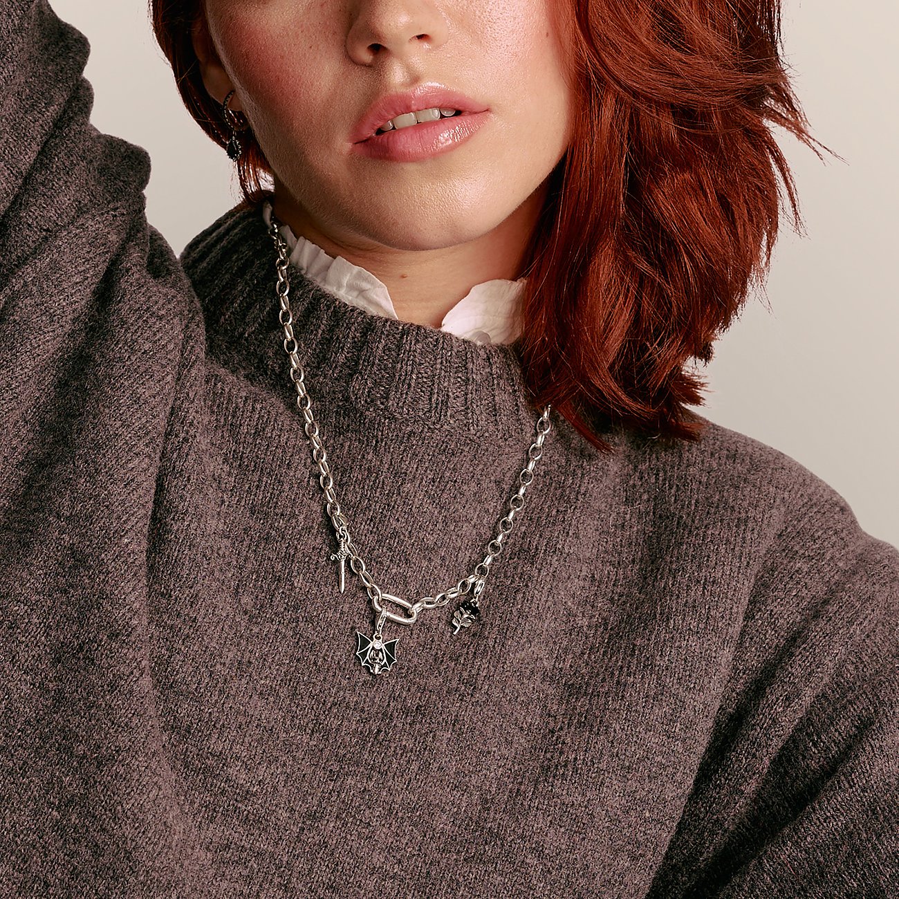 Primo piano di donna con capelli rossi che indossa una collana d'argento Thomas Sabo con pendenti.