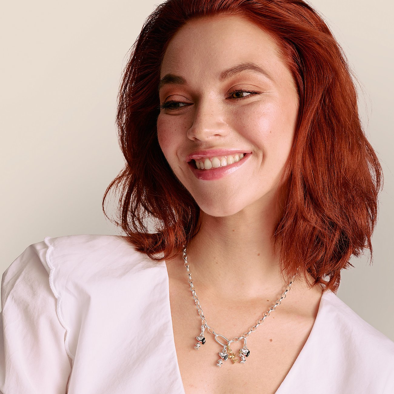 Eine lächelnde Frau trägt eine Thomas Sabo Anhängerkette aus 925er Silber mit mehreren Charms aus Silber und Emaille.