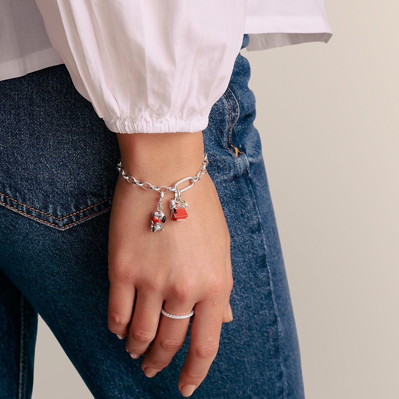 Am Handgelenk einer Person ist ein Thomas Sabo Silberarmband mit zwei Emaille Anhängern zu sehen.