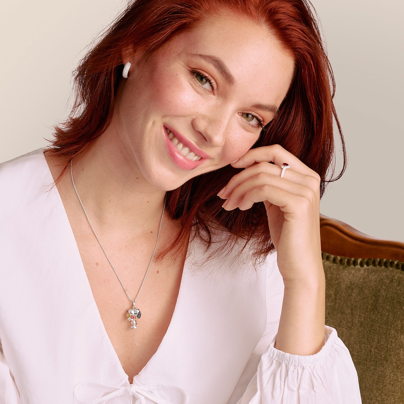 Eine lächelnde Frau mit rotem Haar trägt eine Thomas Sabo Halskette aus Silber mit einem Anhänger und farbigem Zirkonia.