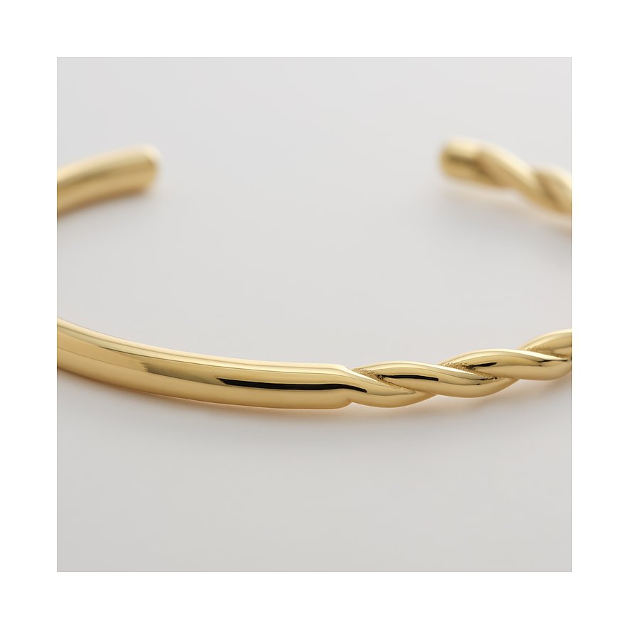 Gros plan d'un bracelet jonc doré Guido Maria Kretschmer en acier, mi-lisse, mi-torsadé.