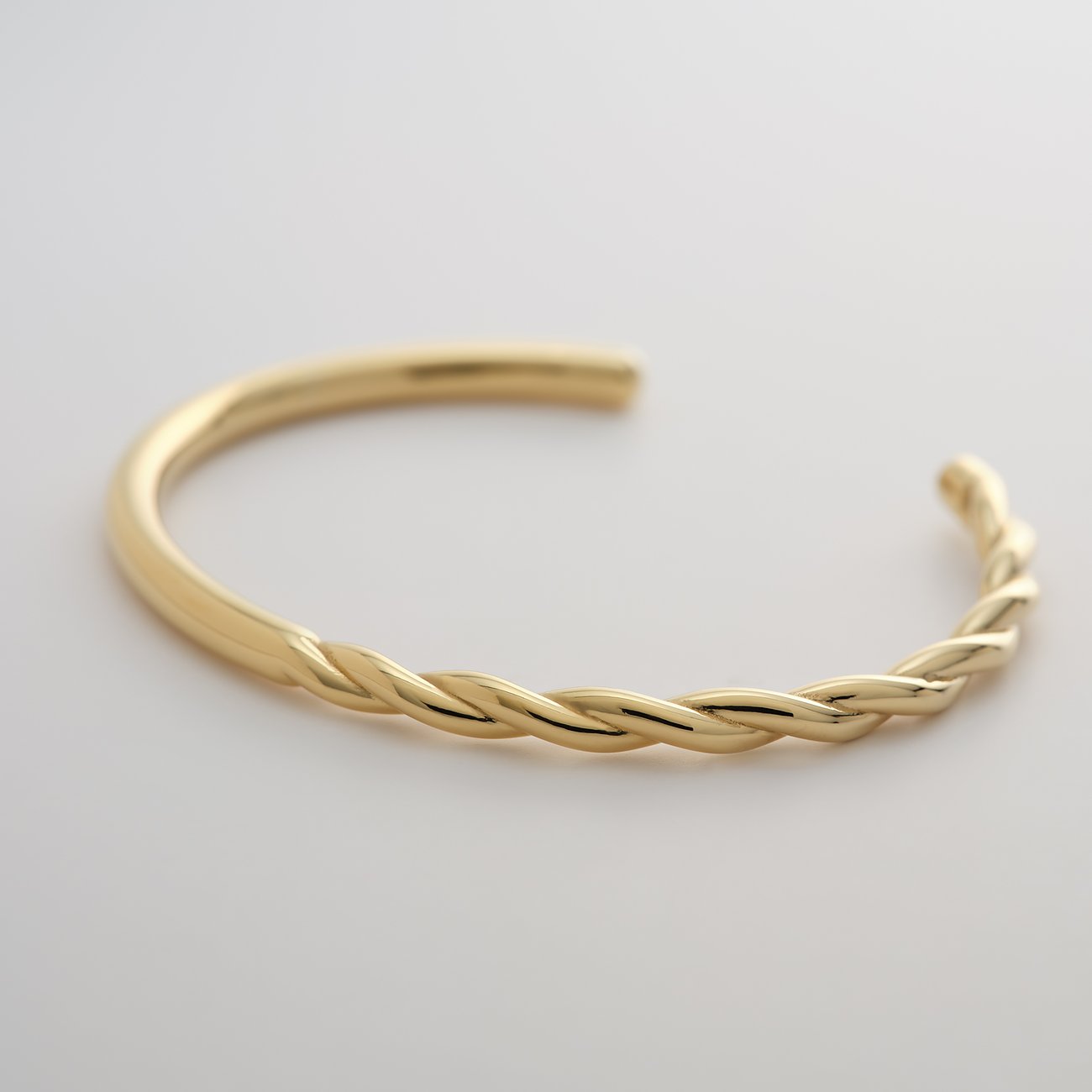 Bracelet Guido Maria Kretschmer en acier inoxydable doré. Une moitié du bracelet est lisse, l'autre moitié est torsadée.