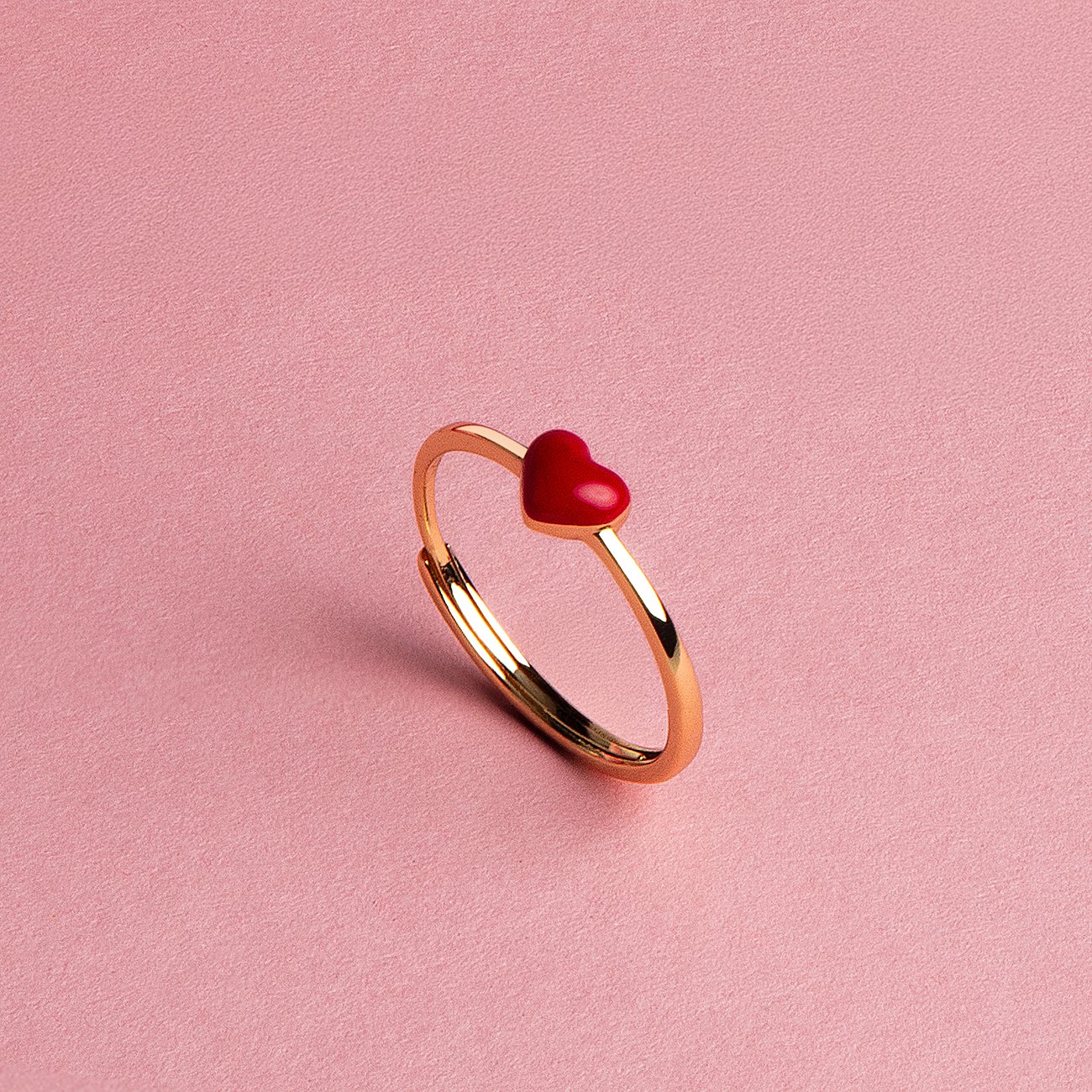 Ein goldfarbener, verstellbarer La Petite Story Ring aus Silber mit einem kleinen roten Herz als zentralem Element.