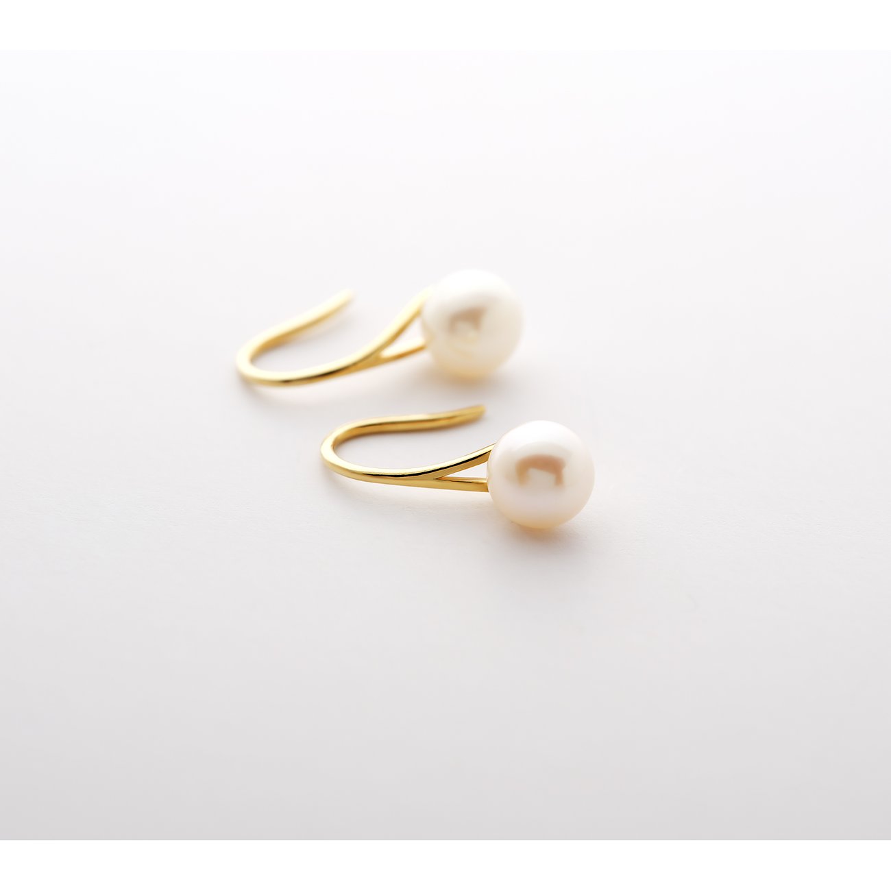 Boucles d'oreilles CHRIST en or jaune 585, ornées de deux perles blanches éclatantes sur des clous en forme de C.