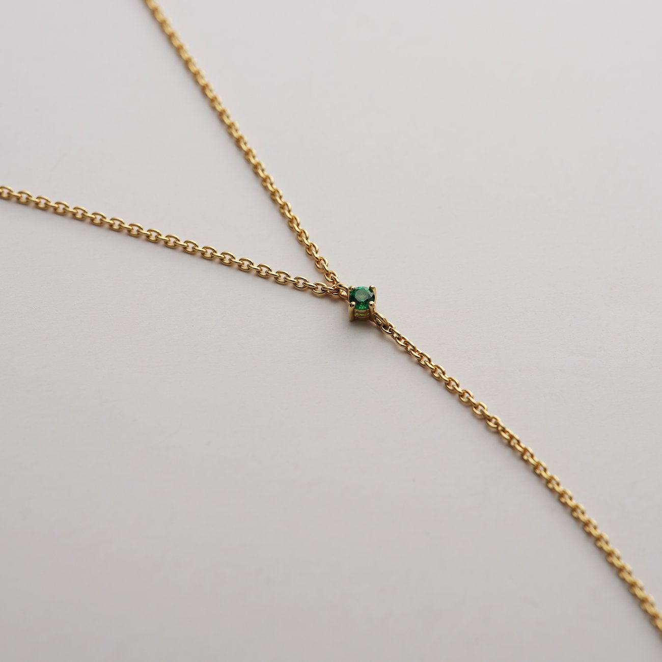 Ein zierliches Guido Maria Kretschmer Y-Collier aus recyceltem, vergoldetem Silber mit einem grünen Zirkonia.