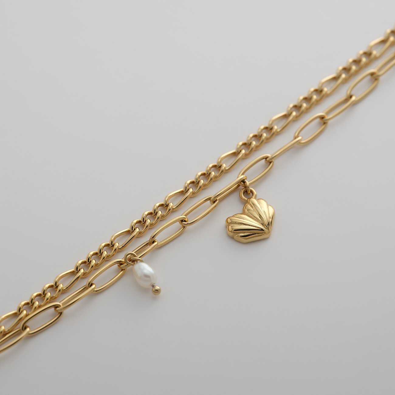 Un bracciale Guido Maria Kretschmer in acciaio inossidabile color oro giallo con perla e ciondolo a cuore.