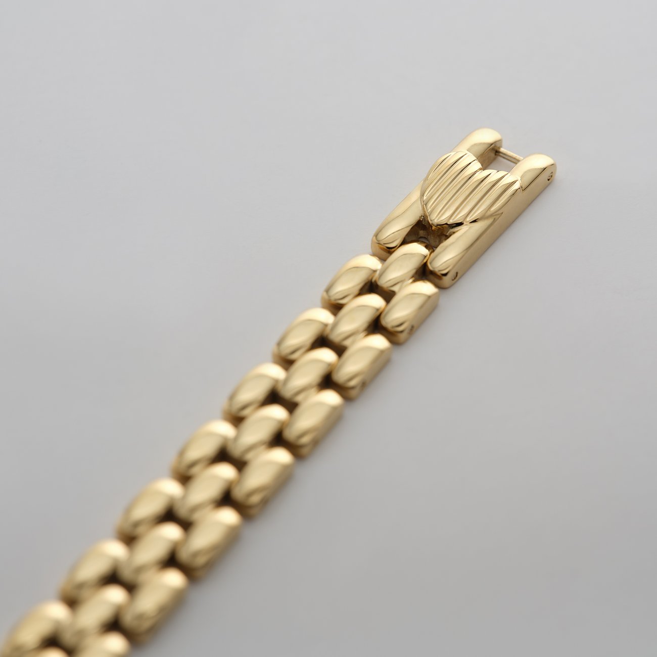 Primo piano di un bracciale dorato Guido Maria Kretschmer in acciaio inossidabile con maglie e chiusura lucida.