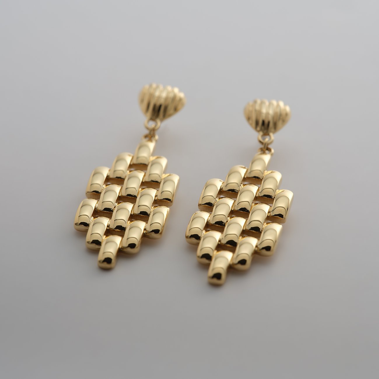 Een paar Guido Maria Kretschmer oorbellen van goudkleurig edelstaal met geometrisch geordende, glanzende buisjes.