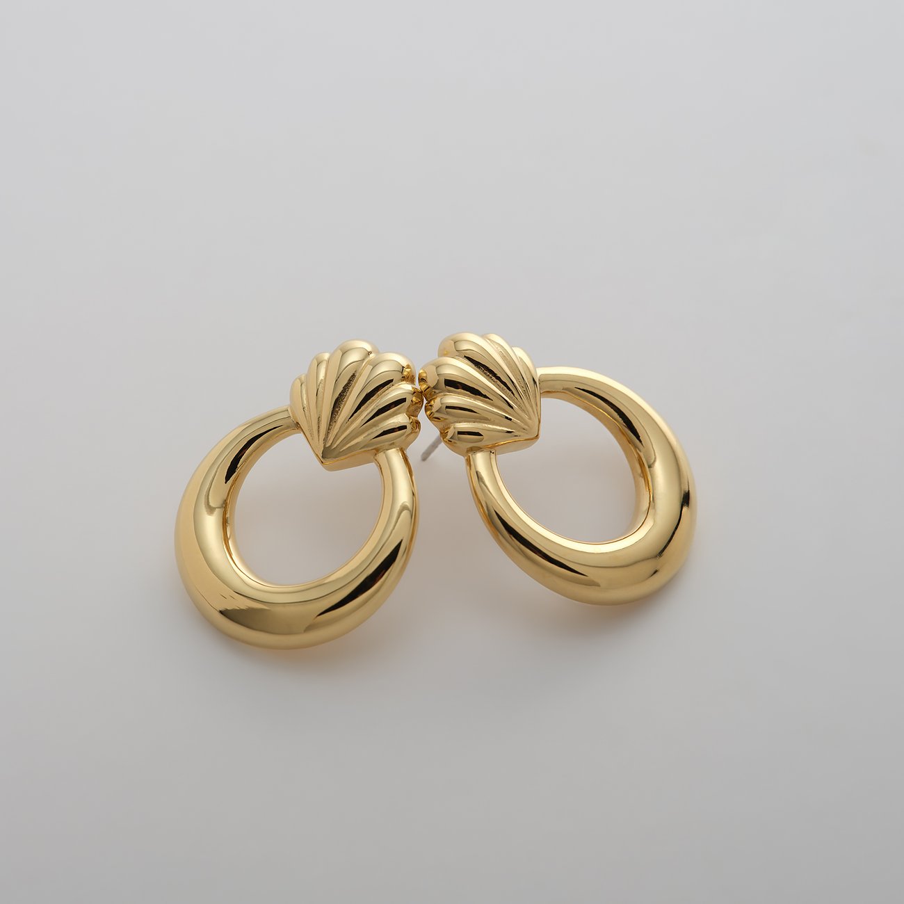 Ein Paar goldfarbene Guido Maria Kretschmer Ohrringe aus Edelstahl mit geriffelten Muschelmotiven und ovalen Anhängern