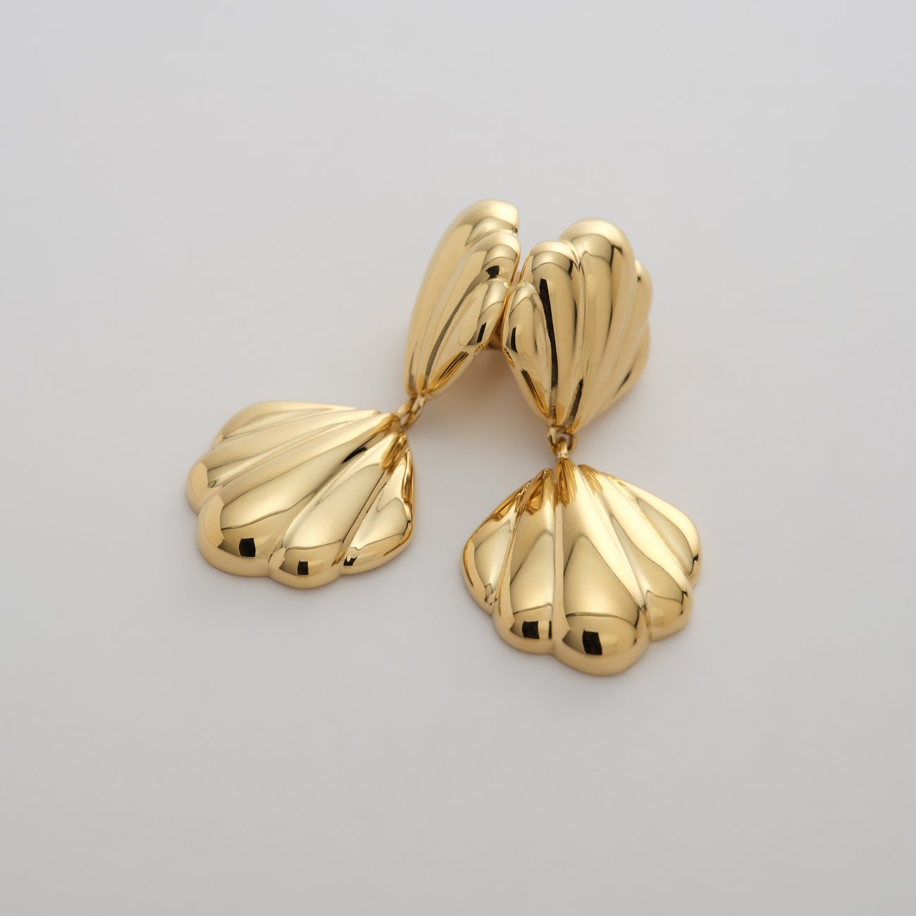 Ein Paar goldfarbene Guido Maria Kretschmer Ohrschmuck aus Edelstahl in gewelltem Muschelschalen-Design.