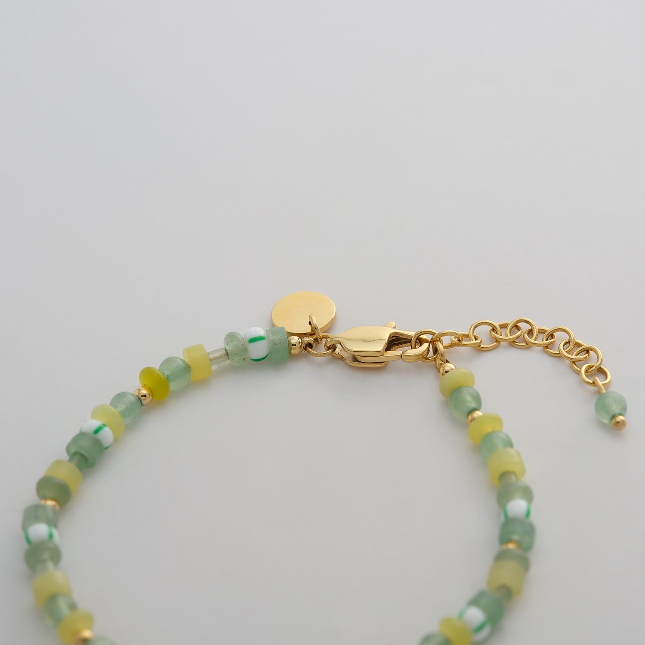 Guido Maria Kretschmer Armband aus goldfarbenem Edelstahl mit bunten Glassteinen und Verschluss.